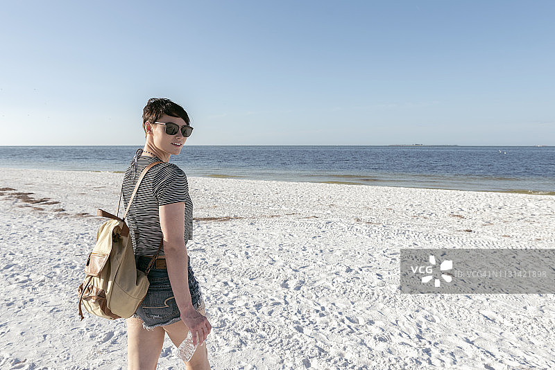 一个年轻女子在海滩上散步图片素材