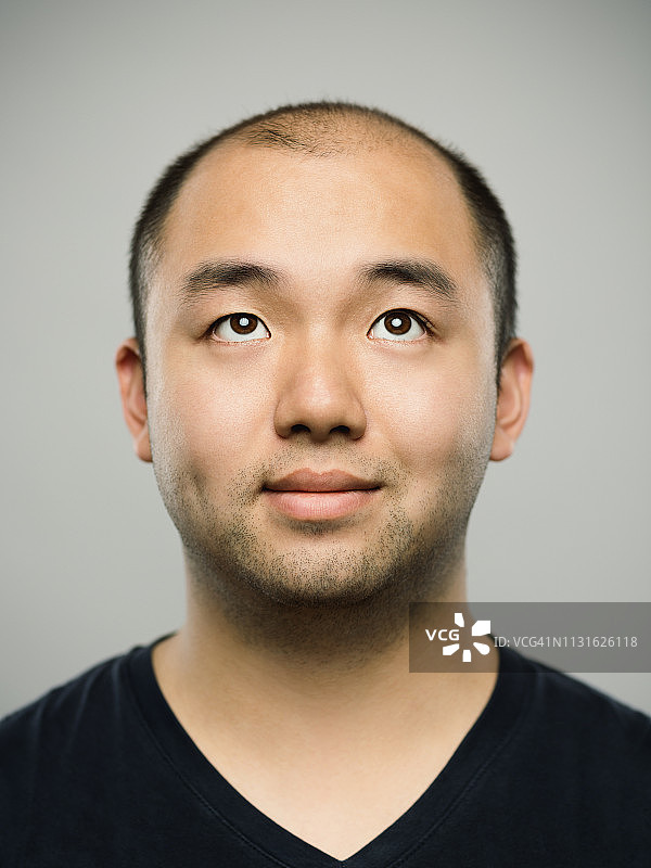 这是一个真正的年轻的中国男人的肖像，脸上带着快乐的表情，仰视着图片素材
