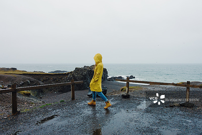 一名年轻女子在雨天的海滩上散步图片素材