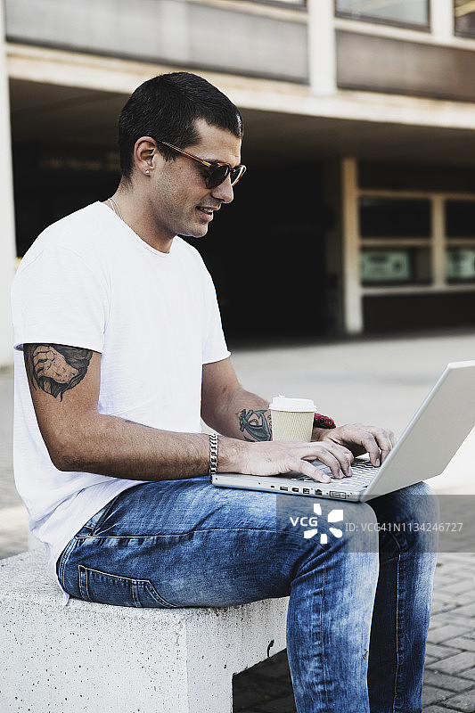 年轻人坐在户外使用笔记本电脑图片素材