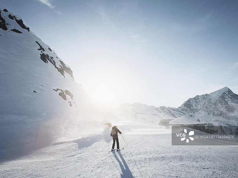 年轻的女滑雪者滑雪在阳光下的积雪覆盖的景观，阿尔卑斯恰姆波里诺，皮埃蒙特，意大利图片素材