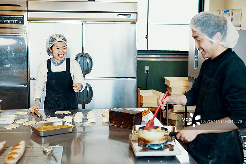 一对中年夫妇在一个工业厨房里为他们的小企业烘焙图片素材