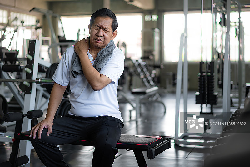 亚洲老年人在健身房锻炼时肩膀疼痛。图片素材