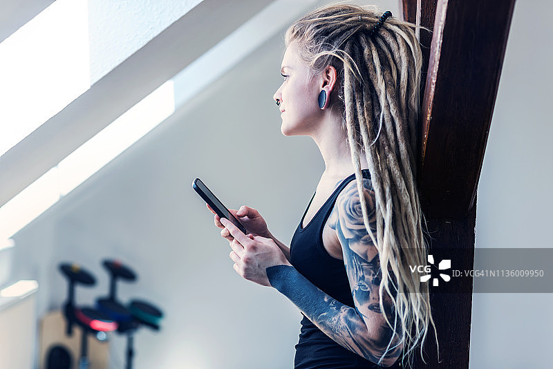 一个有纹身的女人在家里用手机的肖像图片素材