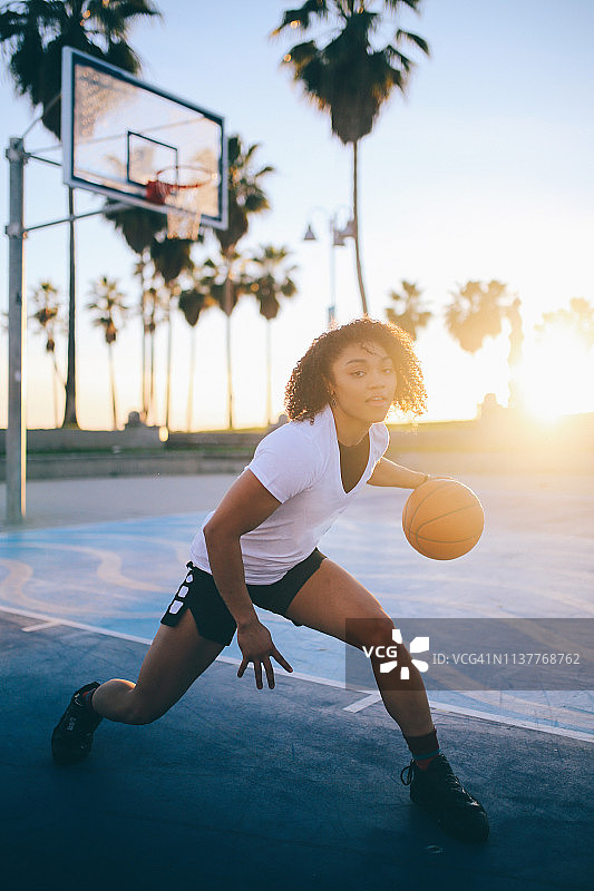 一位年轻女子在加利福尼亚的威尼斯练习篮球运球图片素材