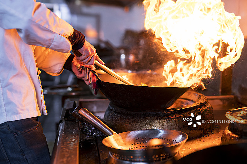 厨师在厨房炉子上用煎锅用火焰烹饪图片素材