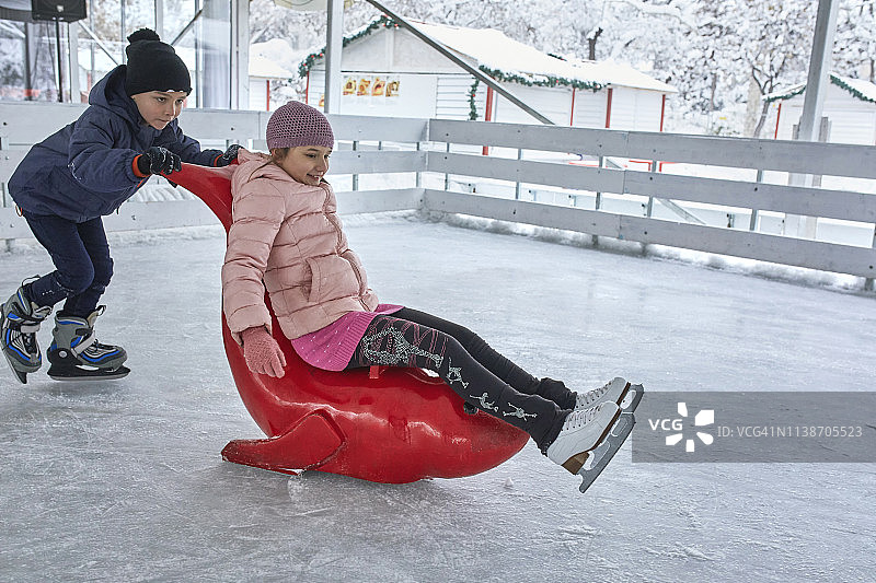 哥哥推着妹妹在溜冰场上，坐在海豹雪橇上图片素材