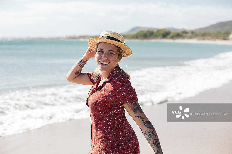 西班牙，马略卡岛，快乐的年轻女子纹身在海滩上的肖像图片素材
