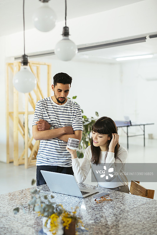 两个同事在桌子上用笔记本电脑一起工作图片素材