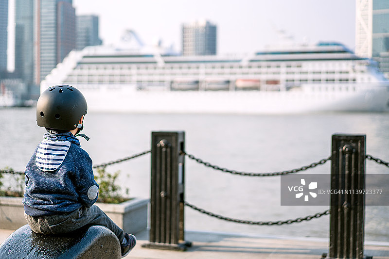 一个小男孩坐在码头上，看着别处图片素材