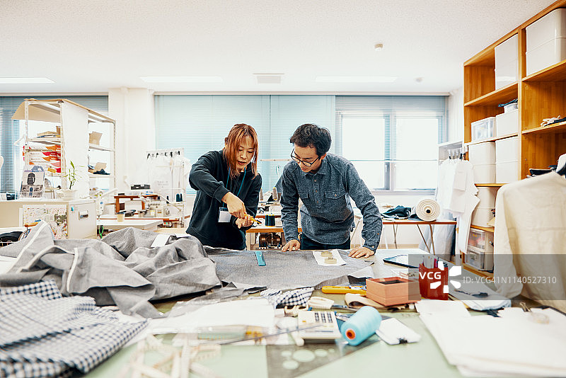 两个中年设计专业人员一起工作在纺织制造工作室图片素材