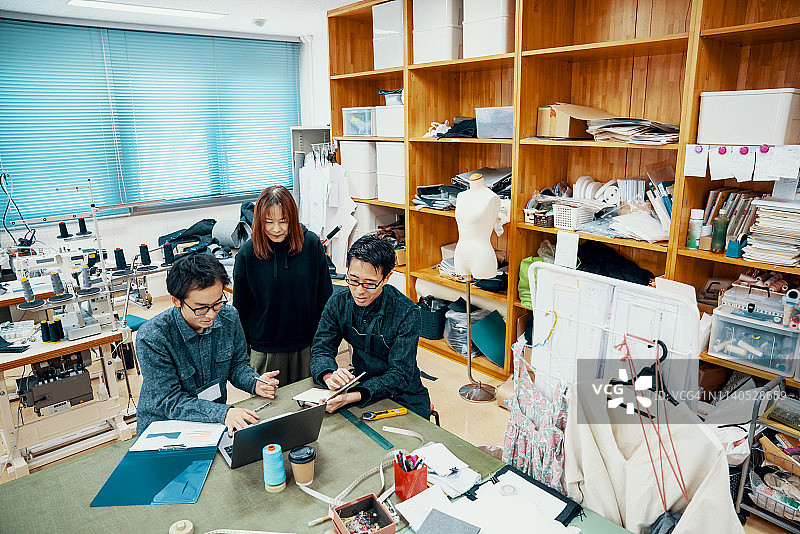 在纺织厂的电脑前工作的中年设计专业人员图片素材