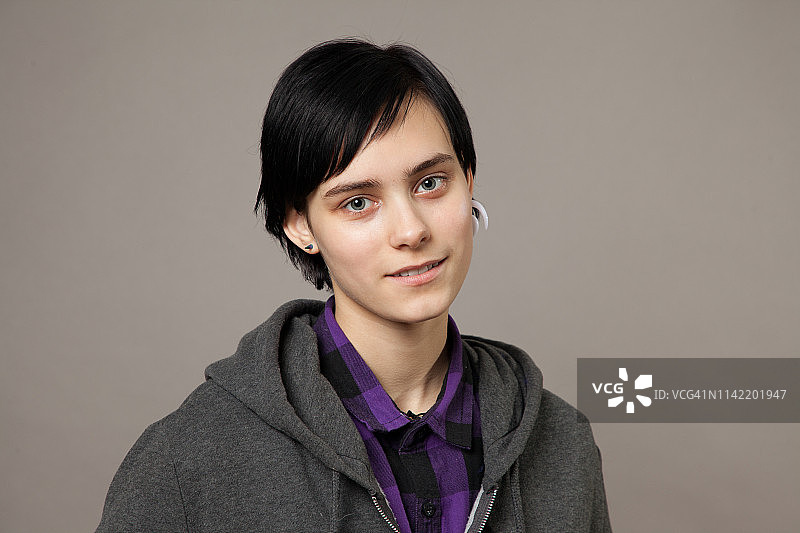 一个迷人的18岁女人的工作室肖像与短发在一个灰色的背景图片素材