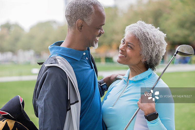 快乐的老非裔美国人夫妇在高尔夫球场上看着对方图片素材