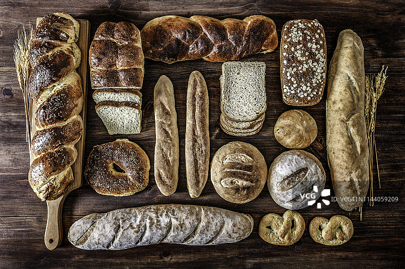 手工烘焙:在乡村厨房里的新鲜混合面包、面包卷和配料图片素材