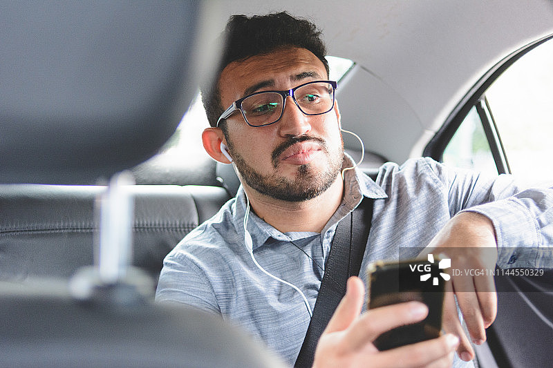 一名男子在汽车后座上用智能手机和司机聊天图片素材