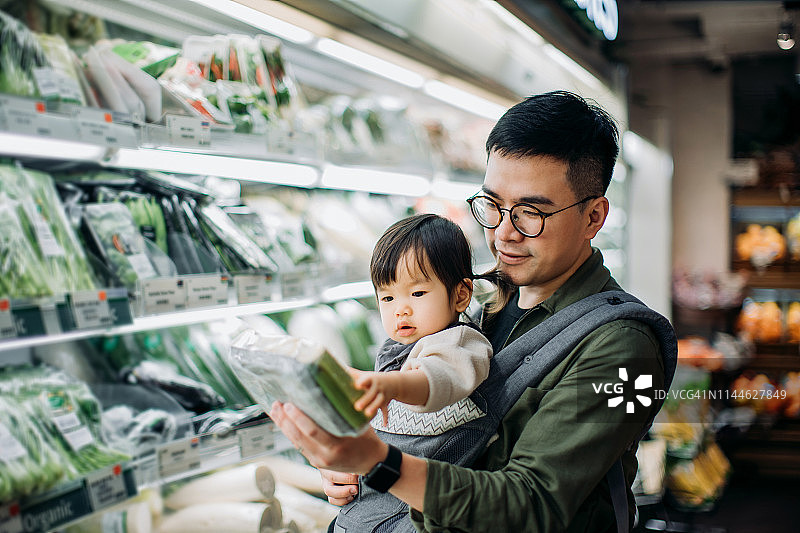 年轻的亚洲父亲和可爱的小女儿在超市买新鲜的有机蔬菜图片素材