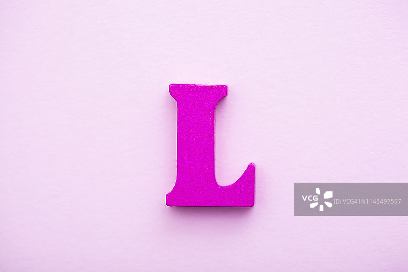 粉色背景上的木制字母L。图片素材