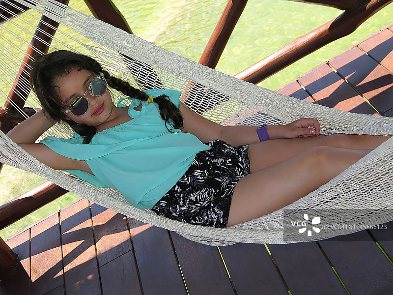 6岁的小女孩在沙滩上的吊床上休息。图片素材