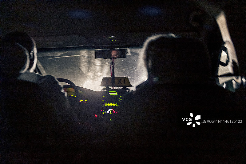 在哈瓦那，一名出租车司机在晚上上班时，前座坐着一名男性乘客。图片素材