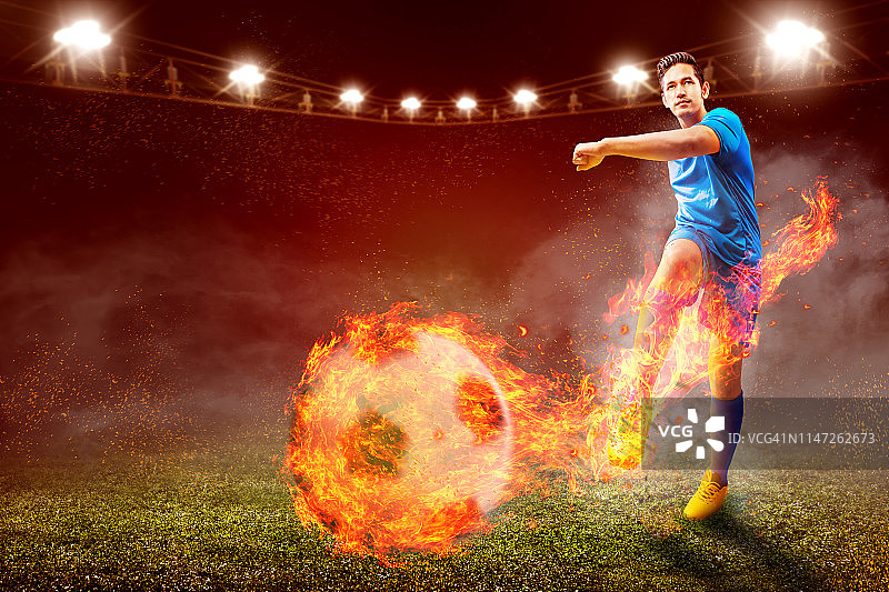 亚洲足球运动员男子蓝色球衣与踢球与火的效果图片素材