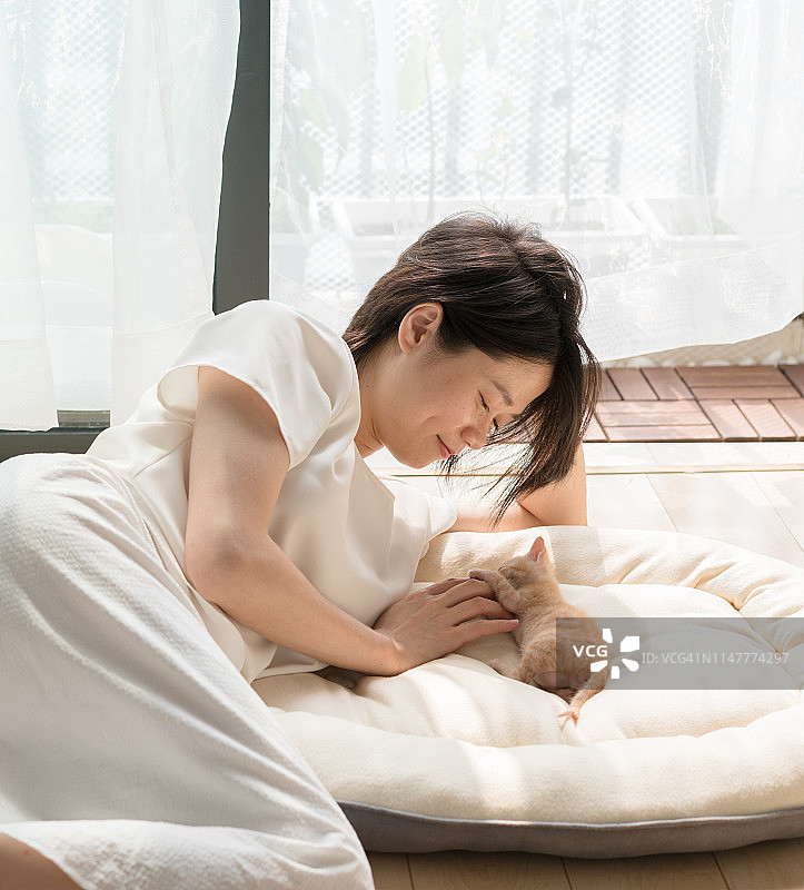 亚洲女人与猫放松在地板上在家里图片素材