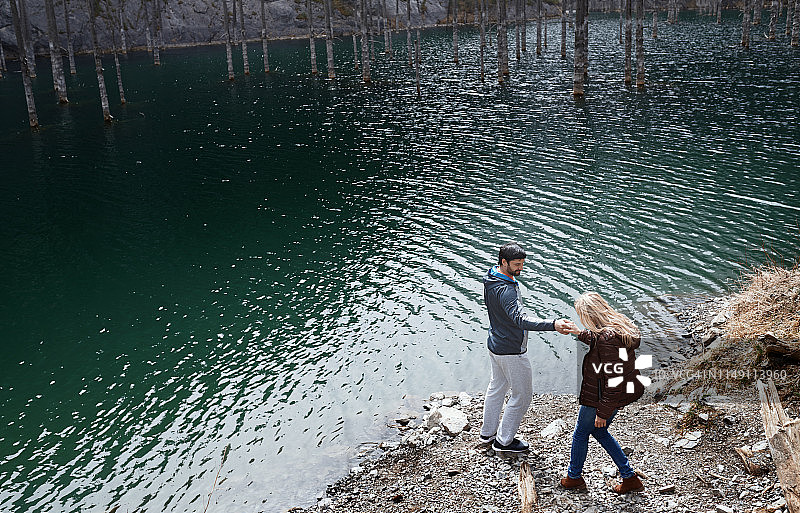 一对爱玩的夫妇在湖边，有淹没的树木图片素材