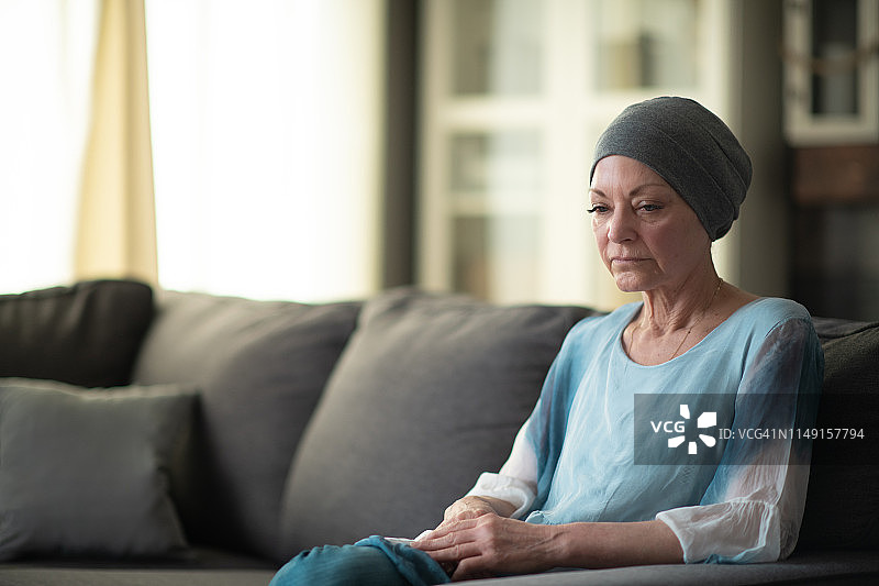 一位身患癌症的老年妇女坐在沙发上。图片素材