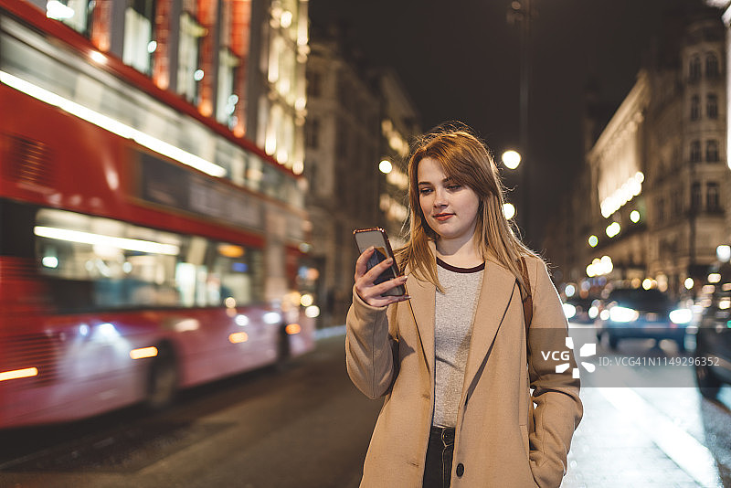 一个正在看手机的女人被伦敦的车流包围了图片素材