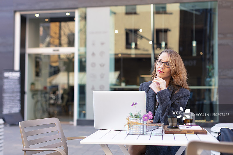 成熟的商业女性在户外咖啡馆使用笔记本电脑图片素材