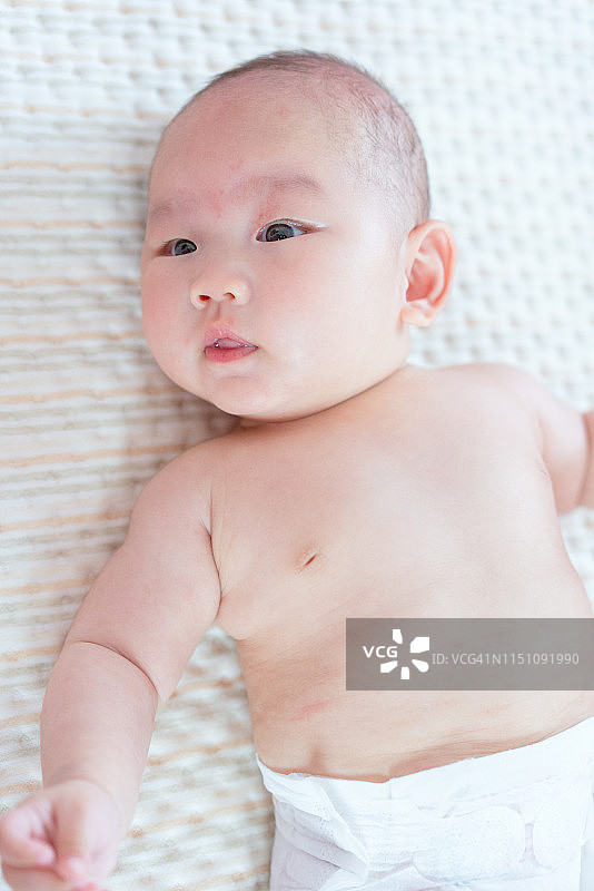 一个亚洲新生儿睁开眼睛看着它。图片素材