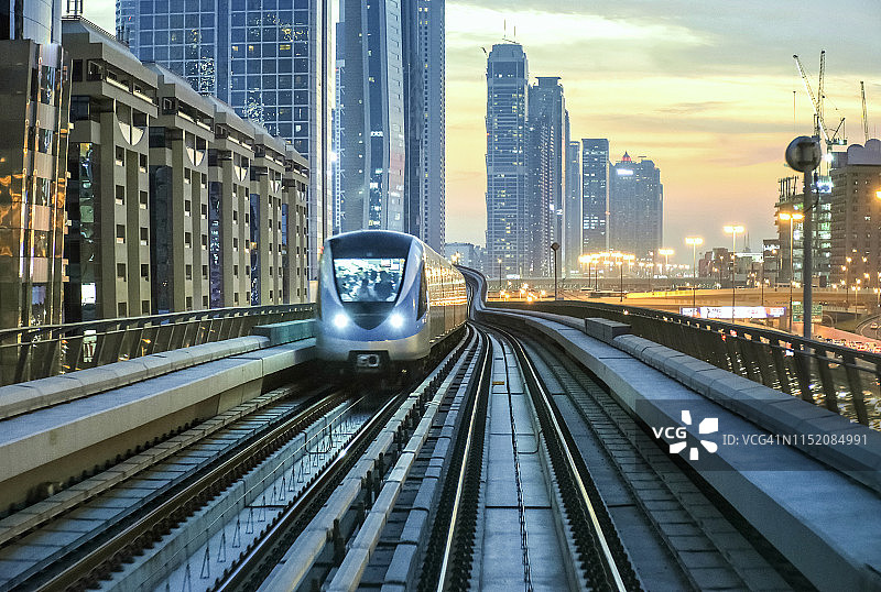日落时分，无人驾驶地铁快速驶近迪拜的地平线图片素材