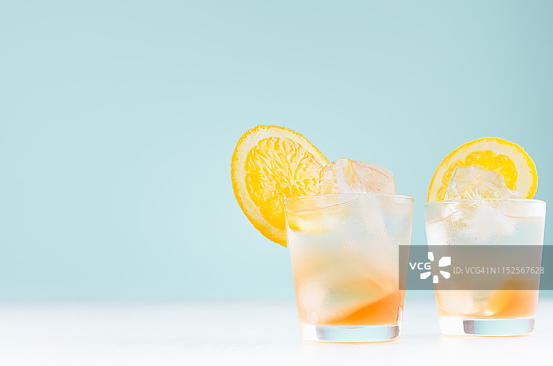 自制橙汁冷饮与橙酒，冰块在雾蒙蒙的小酒杯在柔和的淡蓝色背景。图片素材