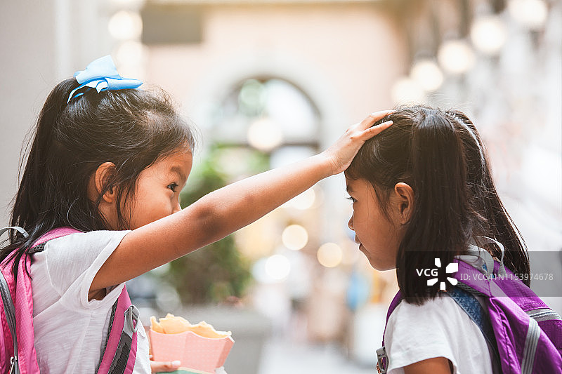 两个可爱的亚洲小女孩拿着书包在学校玩图片素材