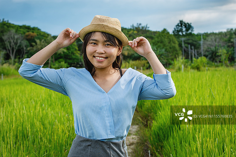 年轻女子戴着帽子，在稻田里微笑着看镜头图片素材