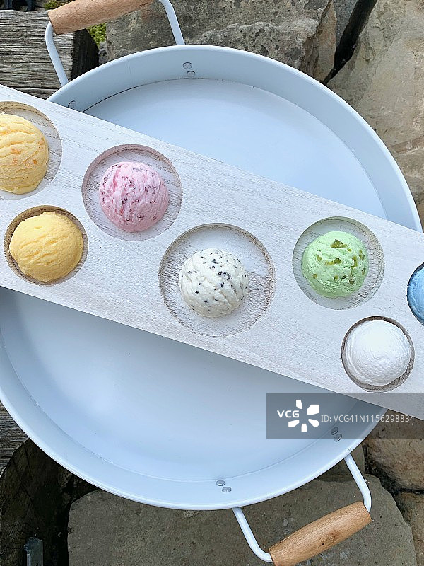 木托盘里的冰淇淋球，从上往下，以花园为背景图片素材