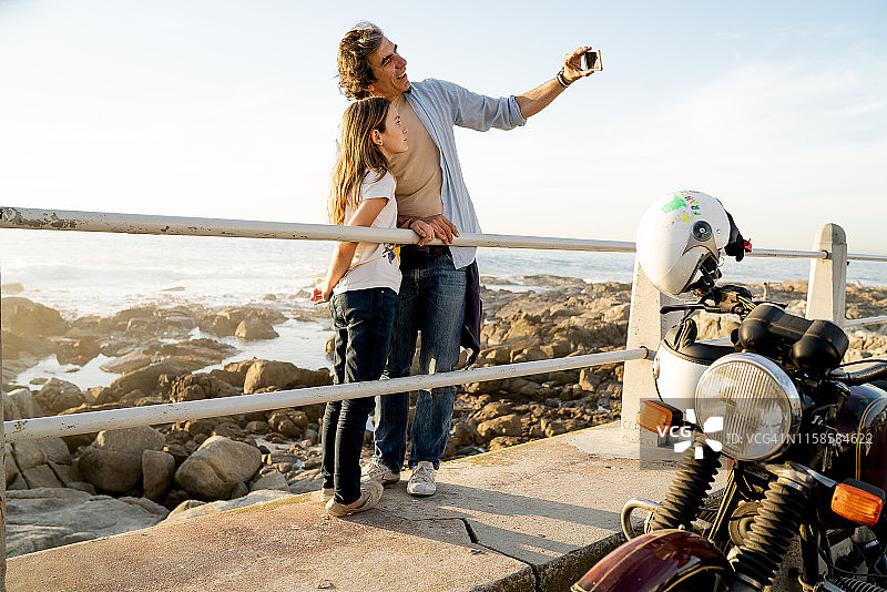 父亲与女儿在海岸与摩托车在前景自拍图片素材