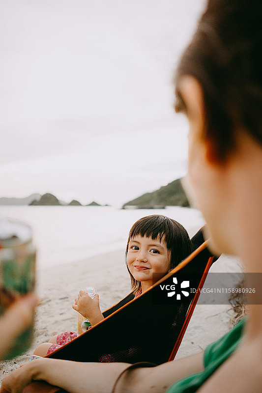 可爱的学前班女孩对着镜头微笑，在日本冲绳的海滩上图片素材