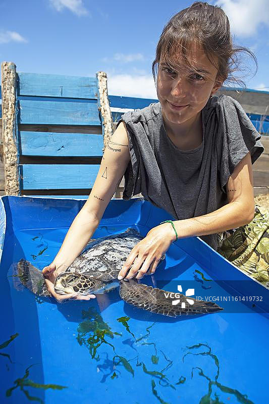 乌拉圭罗查省，Karumbe Centro Tortugas Marinas, 26岁妇女，抱着一只生病的绿海龟(Chelonia mydas)的头图片素材