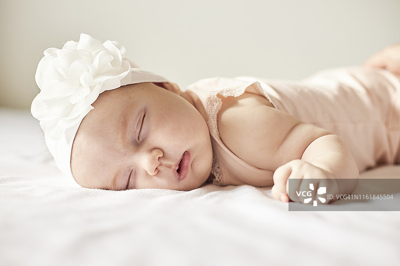 可爱的小女孩头上戴着白色蝴蝶结花睡觉图片素材