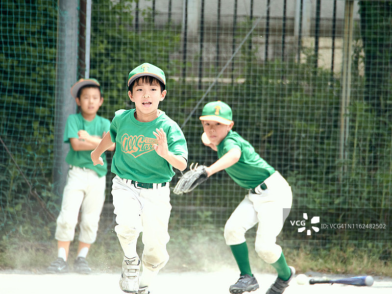 在一场棒球比赛中，那个男孩正以热情的速度向一垒跑去。图片素材