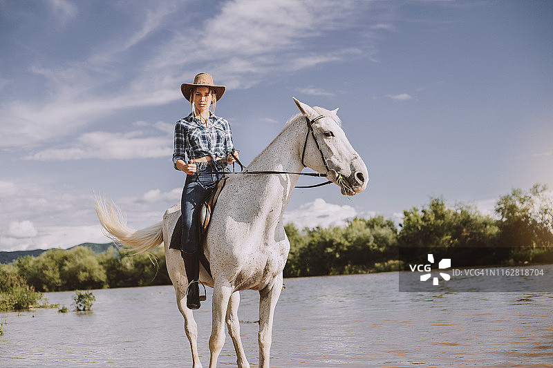 穿着格子衬衫的漂亮女牛仔骑着白马图片素材