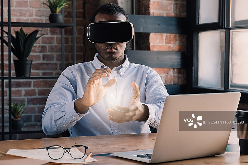虚拟现实的科学概念。非洲工程师在现代办公室里用笔记本电脑使用虚拟现实技术图片素材