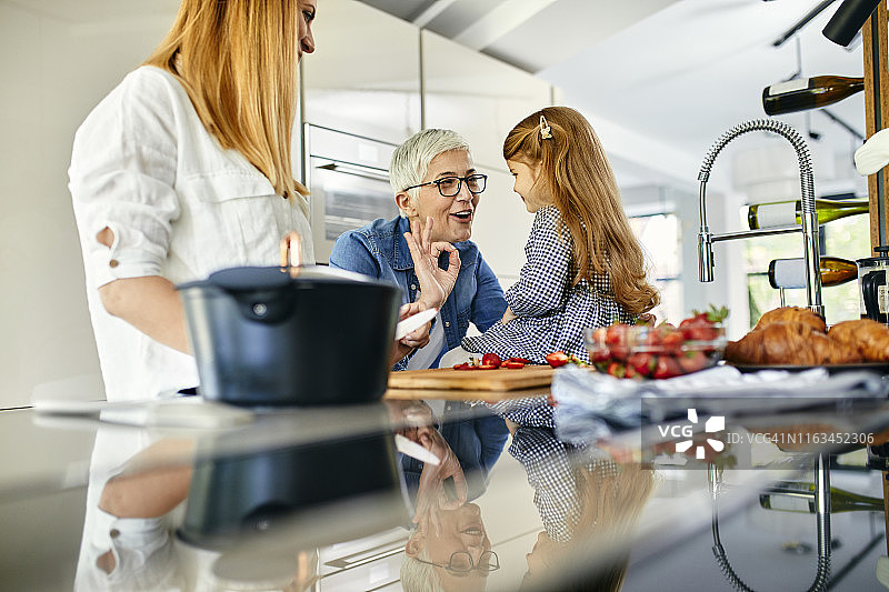 母亲、女儿和祖母在厨房里切草莓，玩得很开心图片素材