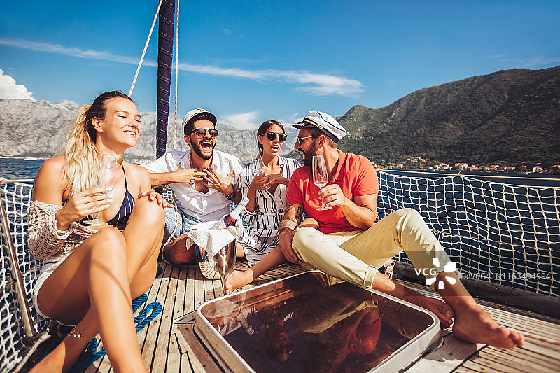 微笑的朋友坐在帆船甲板上玩得很开心。度假、旅游、出海、友谊、为人理念图片素材
