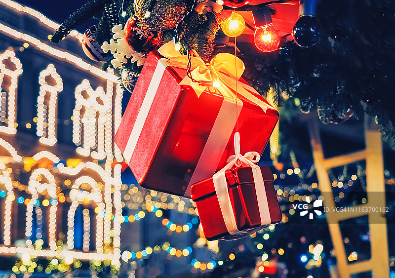 圣诞装饰品，礼品盒，灯饰花环上的冷杉树灯在建筑背景。图片素材