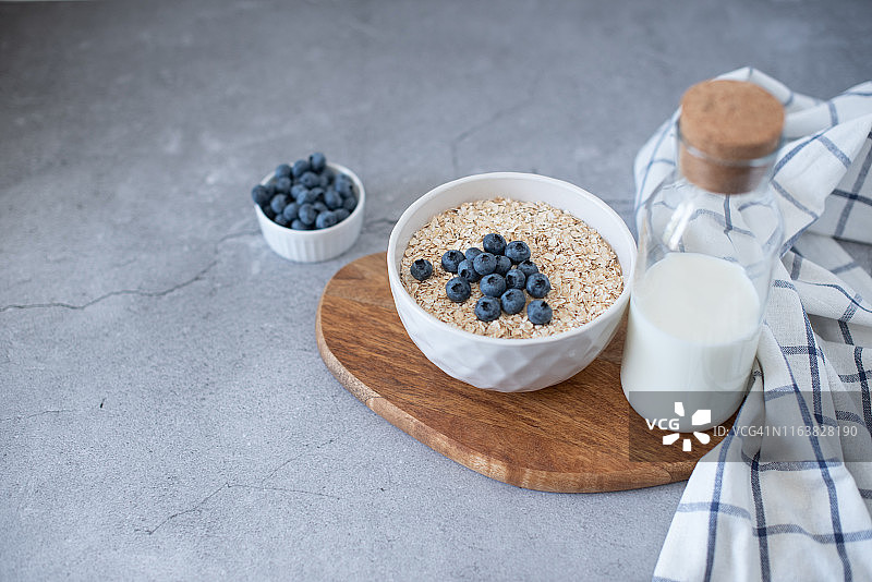 在灰色混凝土背景的碗里自制的蓝莓和草莓燕麦粥。健康的早餐。图片素材