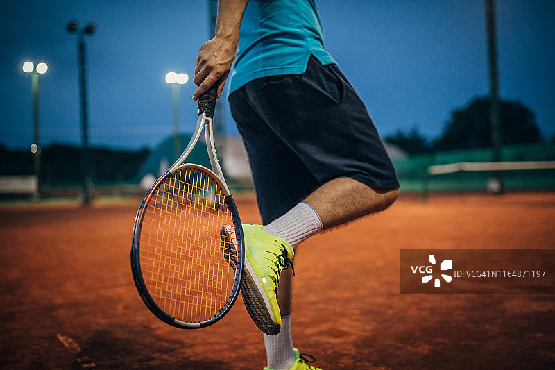 在红土场上手持网球拍的男子网球运动员图片素材