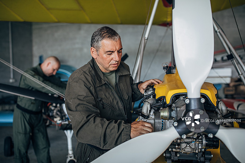 两名飞机机械师在机库修理螺旋桨飞机图片素材
