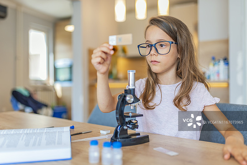 小女孩在使用显微镜时集中注意力。图片素材